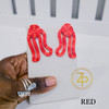 Hand holding contemporary cultural jewelry Iyun Okan red 3D printed symbolic statement earrings by dallas brand zuri perle