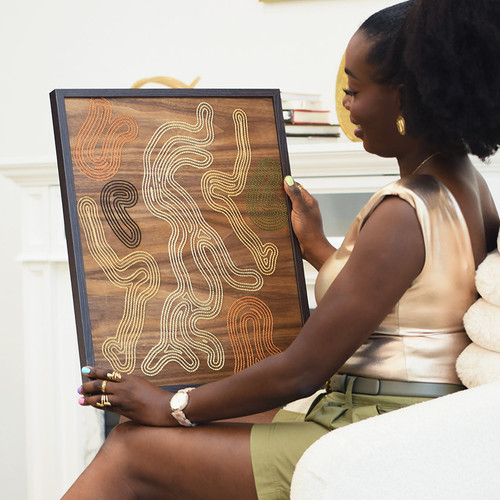 African American Woman Atinuke Adeleke holding Iyun hand embroidered wood contemporary home decor wall art being photographed in a home for Zuri Perle African American Woman Atinuke Adeleke holding Iyun hand embroidered wood contemporary home decor wall art being photographed in a home for Zuri Perle