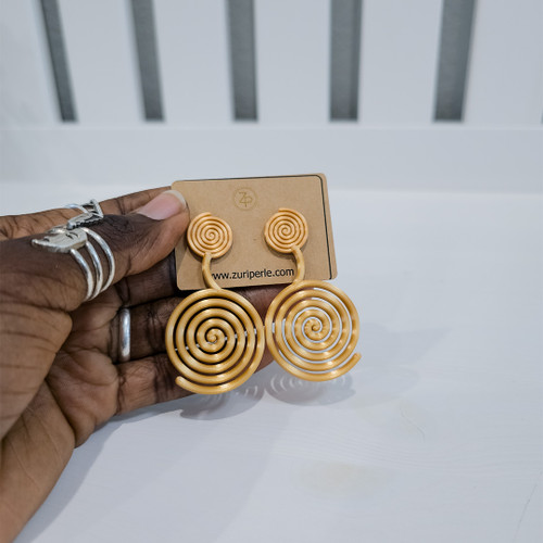Hand holding contemporary cultural jewelry Fumi yellow 3D printed symbolic statement earrings by dallas brand zuri perle