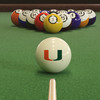 Miami Hurricanes cue ball positioned on green pool table felt in front of a racked set of billiard balls, featuring the orange and green Miami Split-U logo with a pool cue lined up for the break.