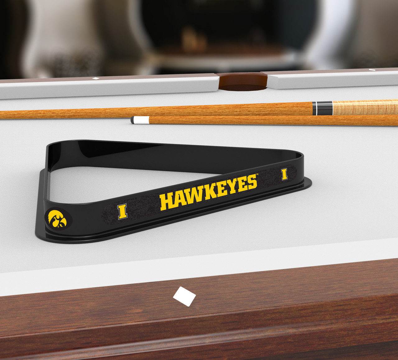 Iowa Hawkeyes billiard triangle displayed on a pool table beneath billiard cues, showcasing the black frame, gold Hawkeyes lettering, and Iowa team graphics in a game room setting.