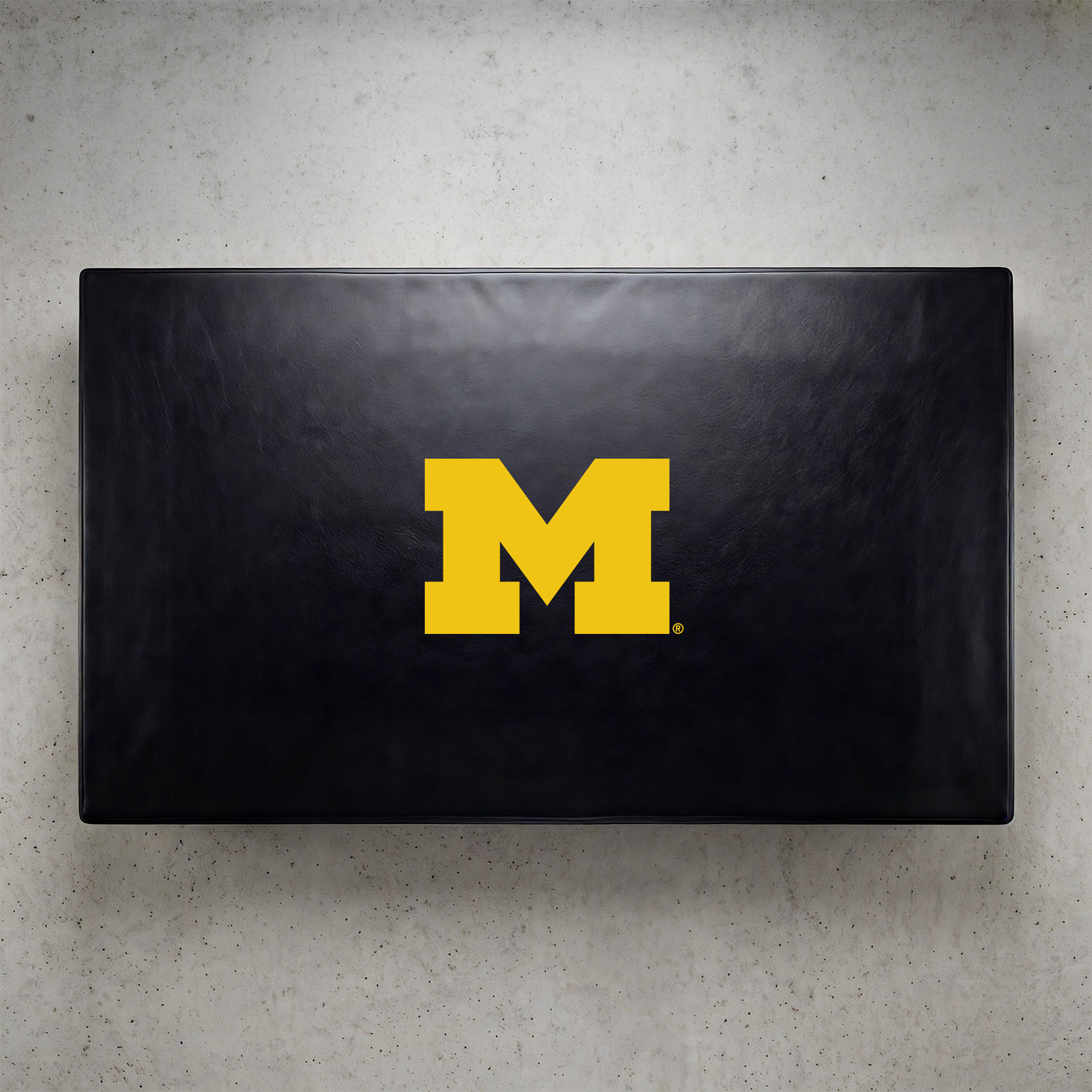 Michigan Wolverines pool table cover shown from above, featuring a black cover design with the yellow Michigan “M” logo centered on the surface. This NCAA billiard table cover is designed to protect the table while showcasing University of Michigan team pride.