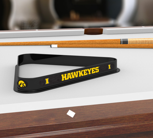 Iowa Hawkeyes billiard triangle displayed on a pool table beneath billiard cues, showcasing the black frame, gold Hawkeyes lettering, and Iowa team graphics in a game room setting.