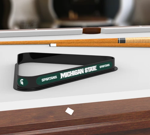 Michigan State Spartans billiard triangle displayed on a pool table beneath billiard cues, showcasing the black frame, green and white team graphics, and Michigan State lettering in a game room setting.