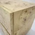 Close-up of a contemporary wooden cabinet with a smooth, light finish and distinctive burl wood patterns. The sleek design conveys modern elegance.