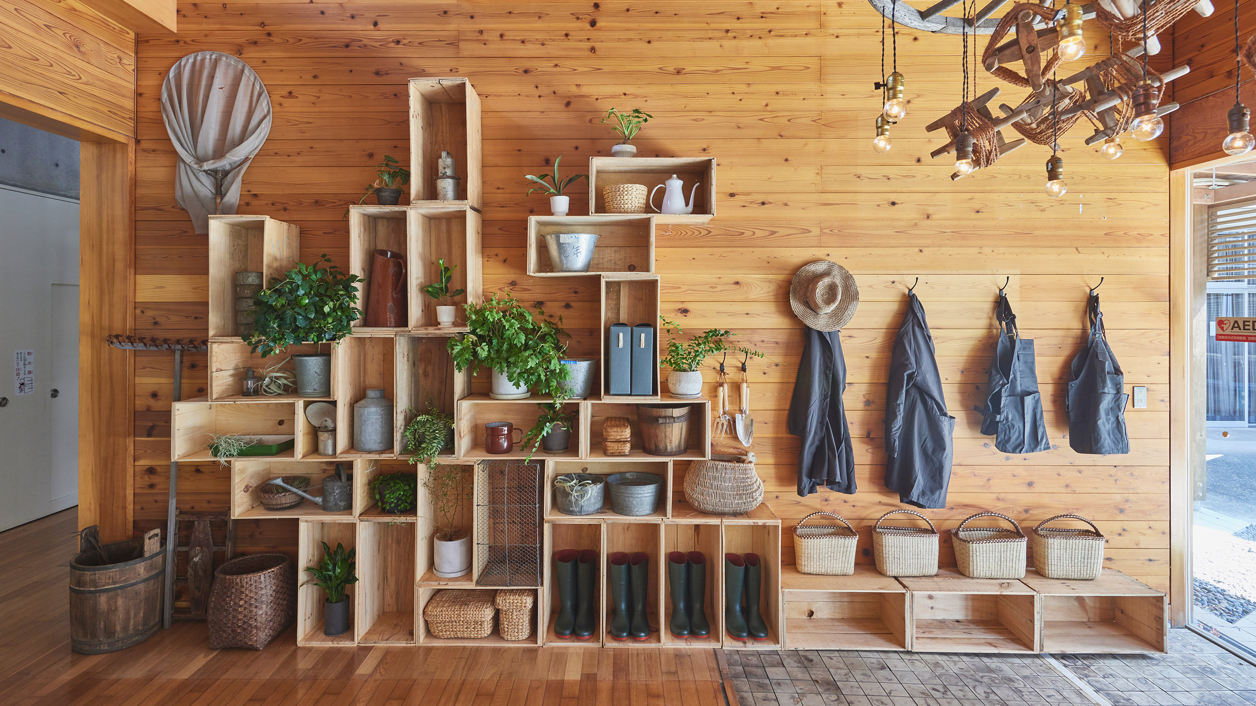 Image of MUJI Base Oikawa entrance with wooden storage crates and coat hooks.
