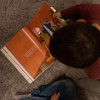Children using a flashlight to reveal the hidden art while reading together