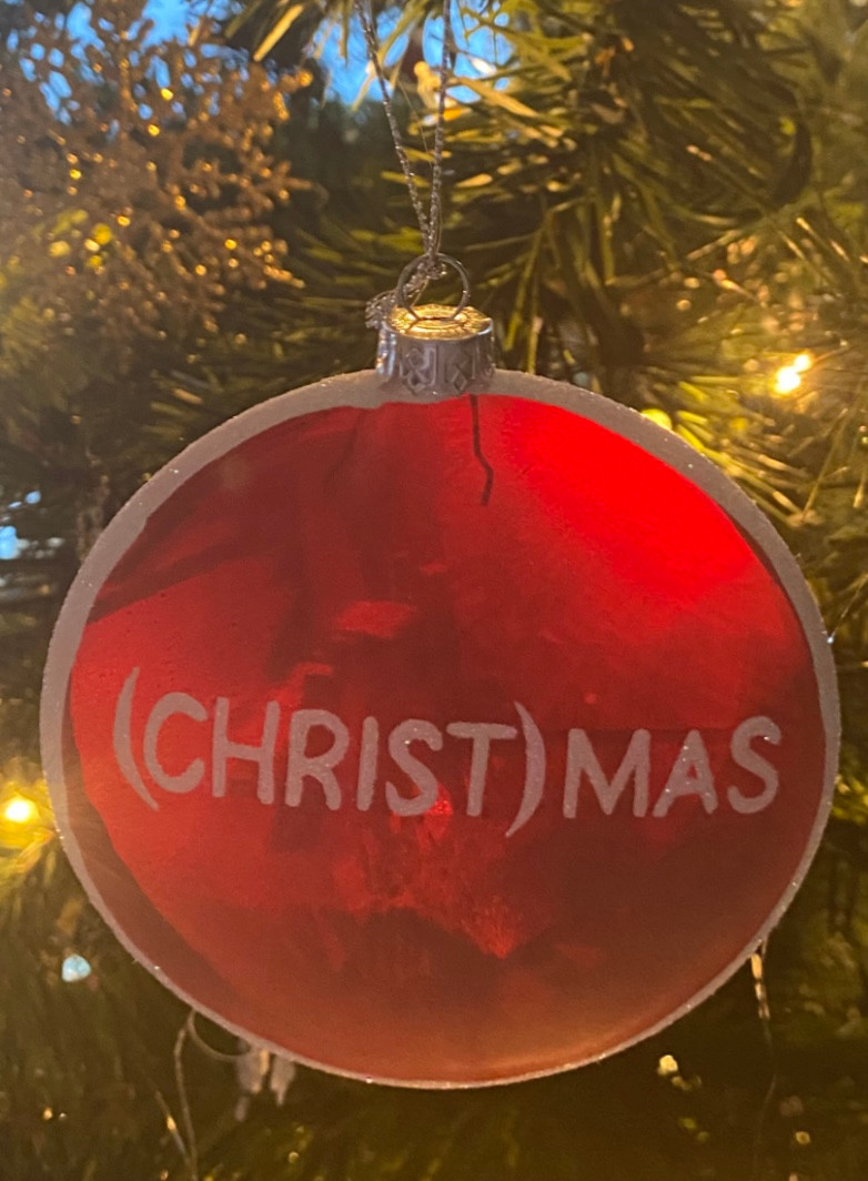 (Christ)Mas Ornament pictured hanging on a Christmas tree