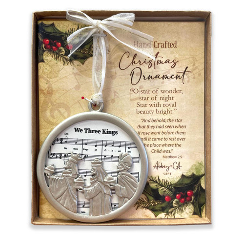 We Three Kings Carol Christmas Ornament shown inside the packaging box with the white and gold hanging ribbon.