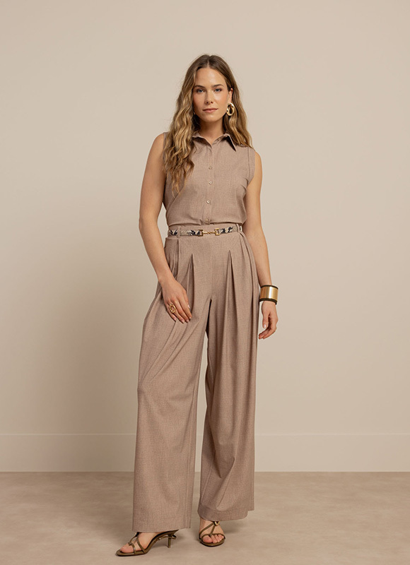 Vrouw draagt een licht beige co ord set met een blouse en wijde broek, gecombineerd met neutrale schoenen. De look benadrukt een comfortabele en stijlvolle minimalistische outfit.