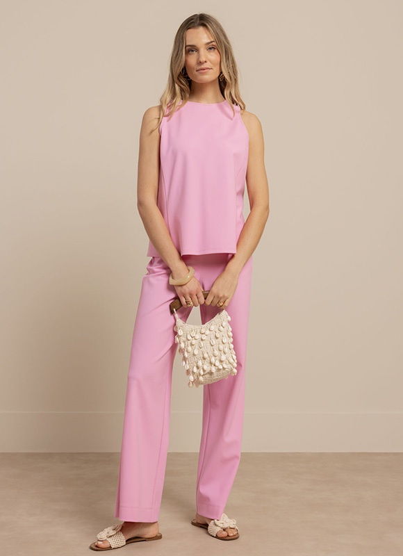 Vrouw draagt een limegroene jumpsuit met strikceintuur en staat rechtop tegen een neutrale achtergrond. De heldere kleur en strakke lijnen zorgen voor een frisse en zelfverzekerde look.