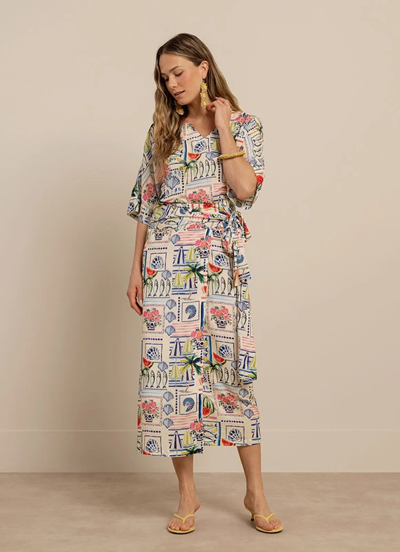 Vrouw draagt een donkerblauwe set met stippenprint en een baret en staat ontspannen met haar hand in haar zak. De speelse print en accessoires geven de look een modieuze en opvallende uitstraling.