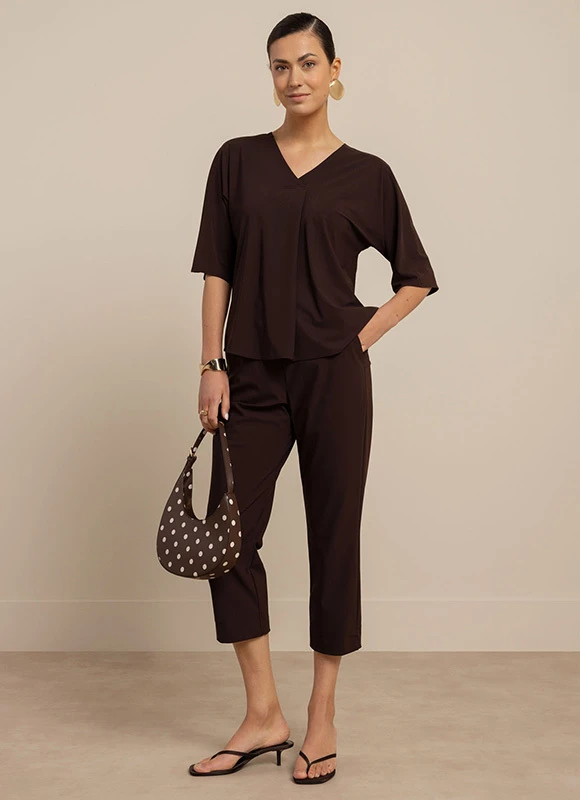 Vrouw draagt een pak met dierenprint en staat met haar hand in haar zij tegen een neutrale achtergrond. De print en pasvorm geven de outfit een krachtige en modieuze uitstraling.