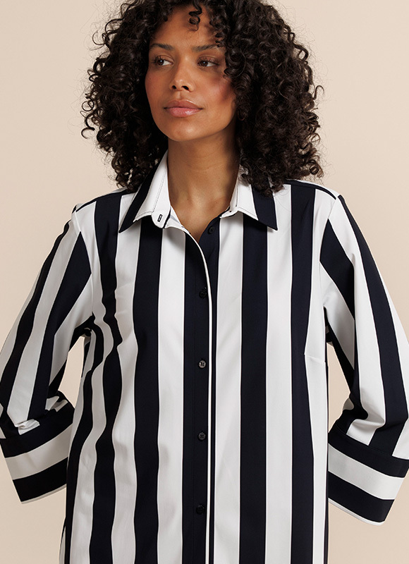 Close-up van een outfit met een donker jasje en een broek met grote stippenprint. Het contrast tussen de prints en kleuren laat zien hoe patronen een look speels en opvallend maken.