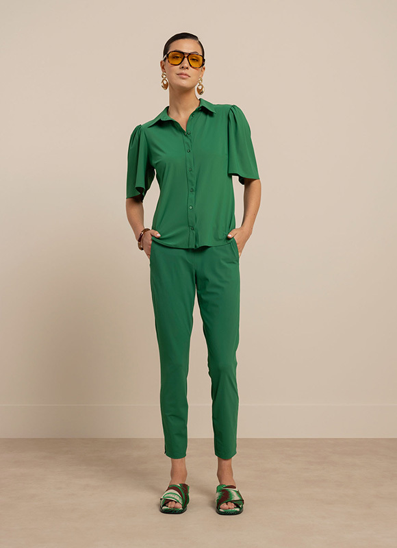 Close up van een groene broek met een striksluiting in de taille en een slanke pasvorm. De afbeelding benadrukt het comfort en de details van de broek.