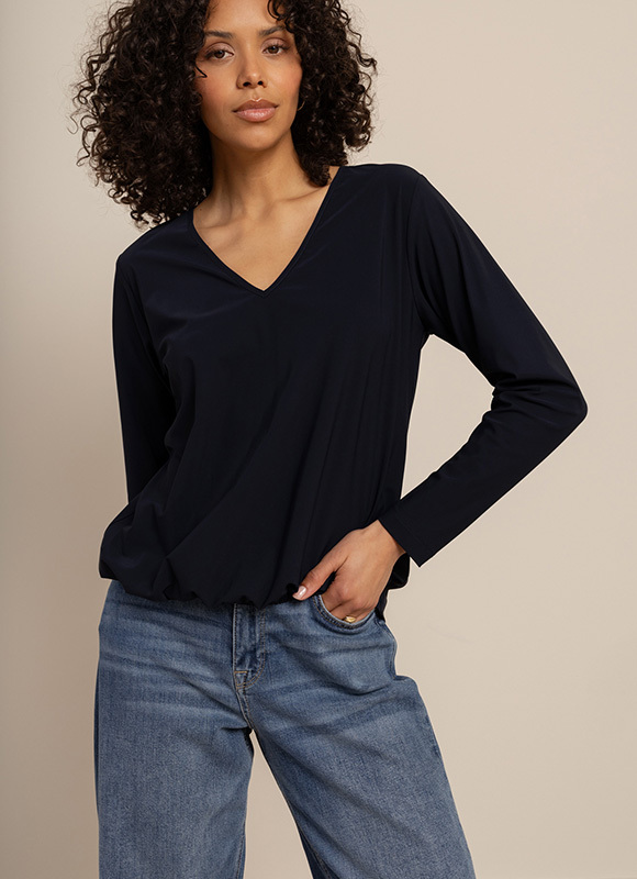 Vrouw draagt een donkerblauwe jumpsuit met wijde pijpen en hakken en poseert zelfverzekerd. De outfit benadrukt hoe een jumpsuit een complete en moderne look creëert.