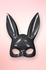 Isolated front view of a glossy black bunny masquerade mask on a pink background.