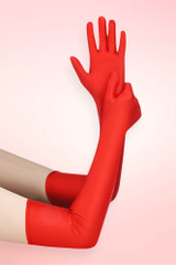 Long red spandex opera gloves in elbow length worn on both arms, one arm raised with open palm, against a pink background.