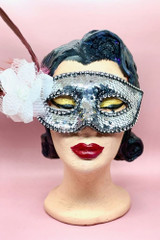 Silver Sequin Masquerade mask with white flower and feather on the side worn by a vintage mannequin head  front view