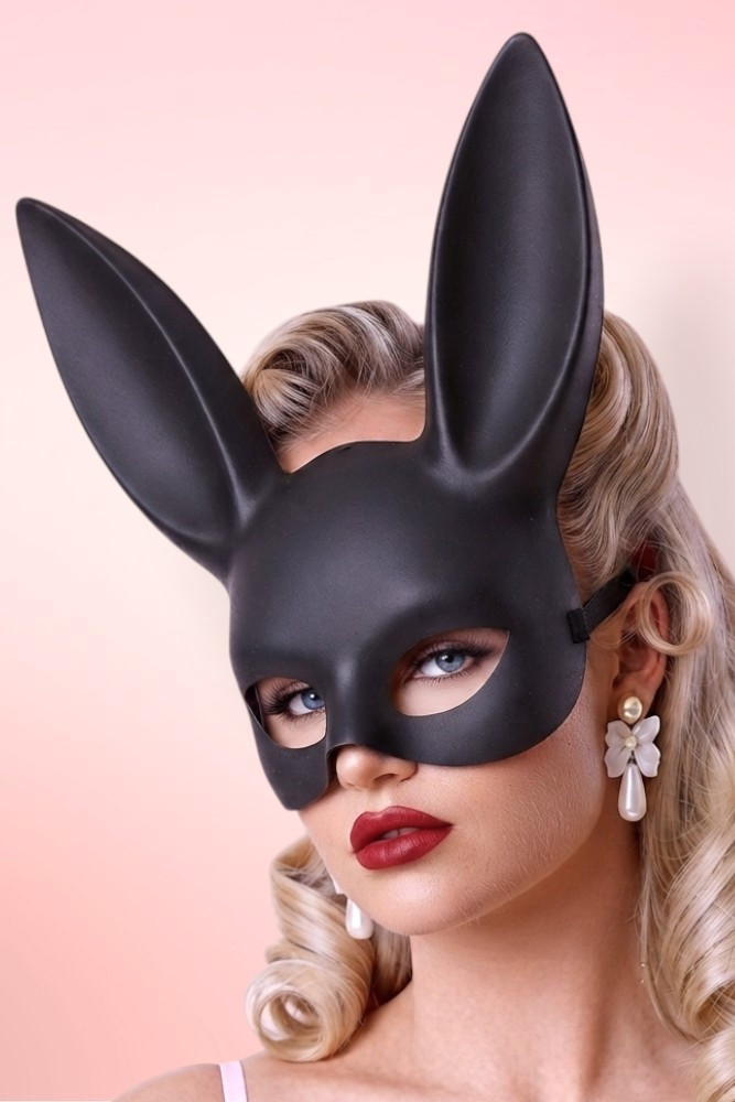 Glamorous blonde wearing a matte black bunny mask and red lipstick.