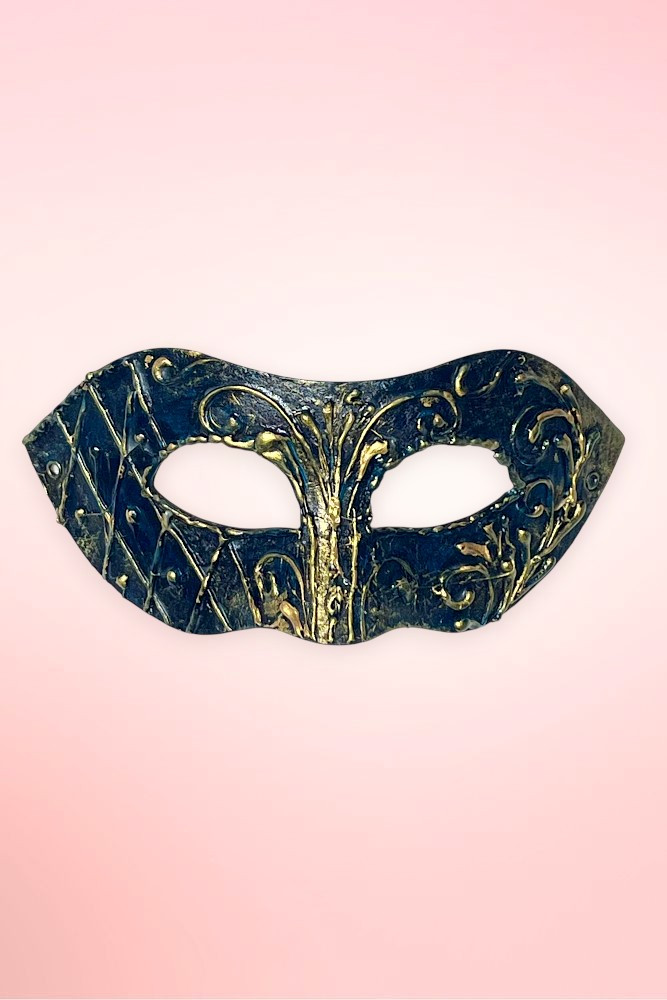 Handmade navy and gold Venetian masquerade mask flat lay on pink background.