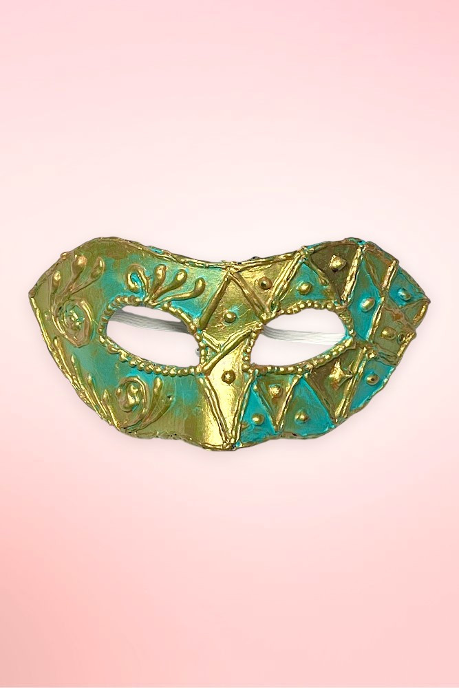 Handmade teal and gold Venetian masquerade mask flat lay on pink background.