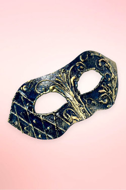 Handmade navy and gold Venetian masquerade mask angled right on pink background.