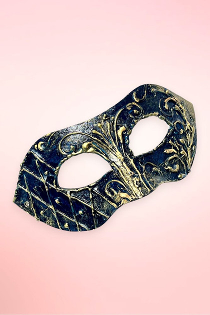 Handmade navy and gold Venetian masquerade mask angled right on pink background.