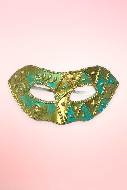 Handmade teal and gold Venetian masquerade mask flat lay on pink background.