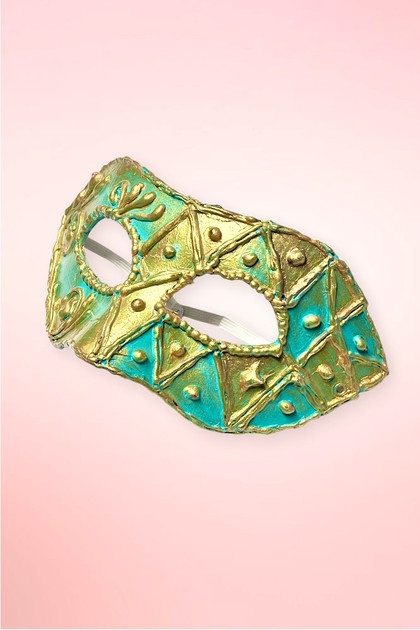 Handmade teal and gold Venetian masquerade mask angled right on pink background showing harlequin geometric panel side.