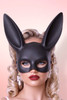 Three-quarter profile of a woman in a matte black bunny masquerade mask.