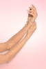 Nude rhinestone fishnet gloves, long opera length with iridescent crystal embellishments, single arm raised against pink background.