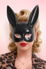 Portrait of a glamorous woman wearing a glossy black bunny mask and red lipstick.