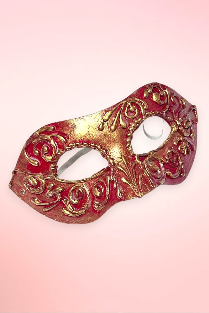 andmade Venetian masquerade mask angled to the left against a light pink background.