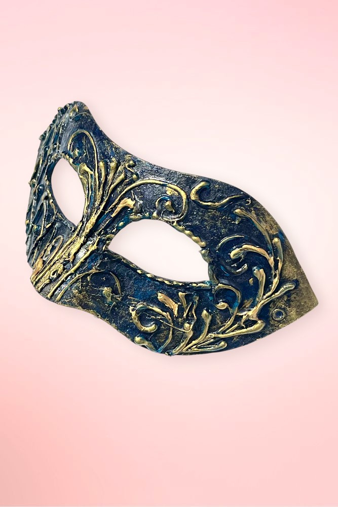 Handmade navy and gold Venetian masquerade mask angled left on pink background showing harlequin geometric panel side.