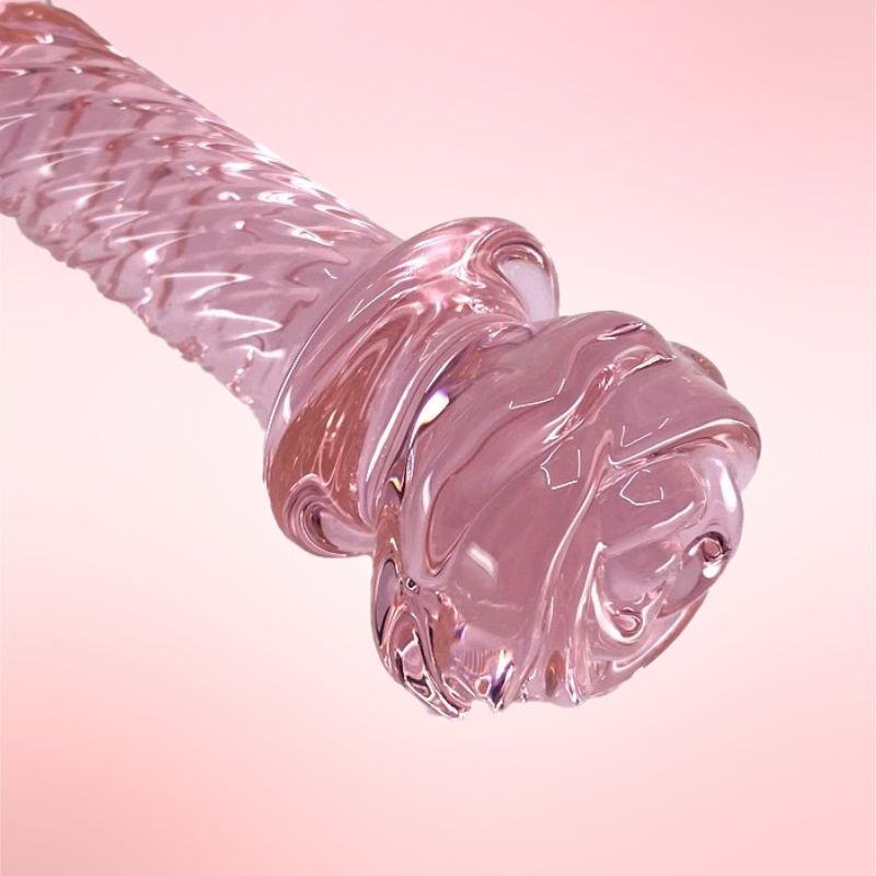 Rose glass dildo wand on a book.