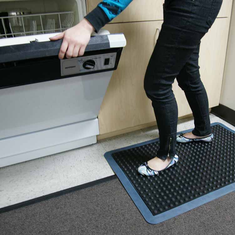 person doing dishes while standing on bubble top anti-fatigue mat