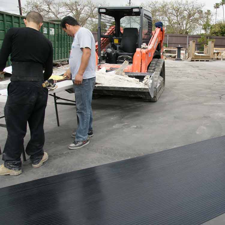 Corrugated composite rib rubber mat on asphalt near two people.