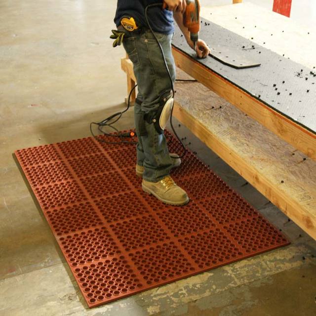 Person using work bench while standing on Red Dura Chef Anti-Fatigue Mat