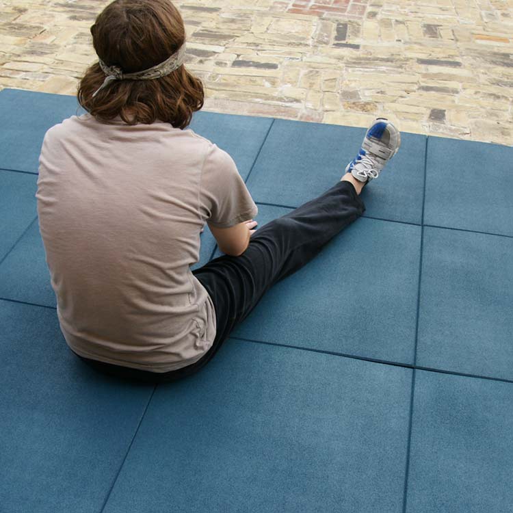 Person ready to stretch sitting on a blue eco-sport tile floor