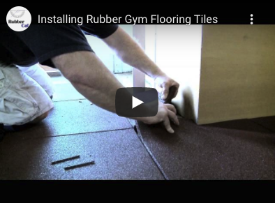 Installing-Rubber-Tiles A person setting a cut rubber tile around a corner