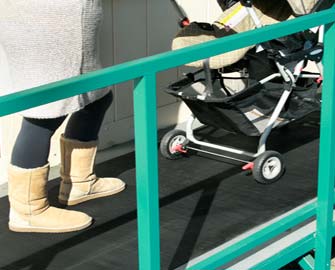 Woman pushing a stroller up ramp that is covered with ramp cleat rubber mat