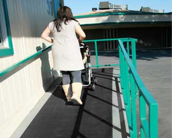 Woman pushing a stroller up a ramp with a Ramp-cleat mat