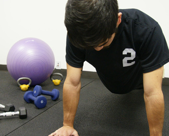 Man exercising on Rubber-Cal Rubber Flooring next to weights