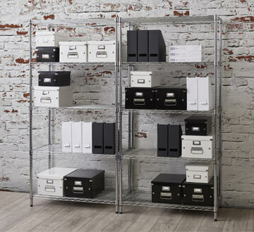 Freestanding chrome wire shelving with white and black boxes inside of it.