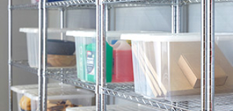 A full warehouse with a single employee, working from his laptop atop a stack of boxes.