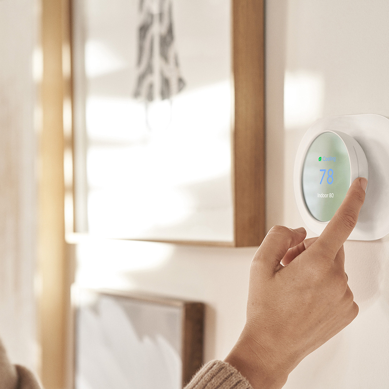 Person adjusting nest thermostat temperature on the wall