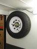 spin on spare tire wall mount inside enclosed trailer with tire secured for travel