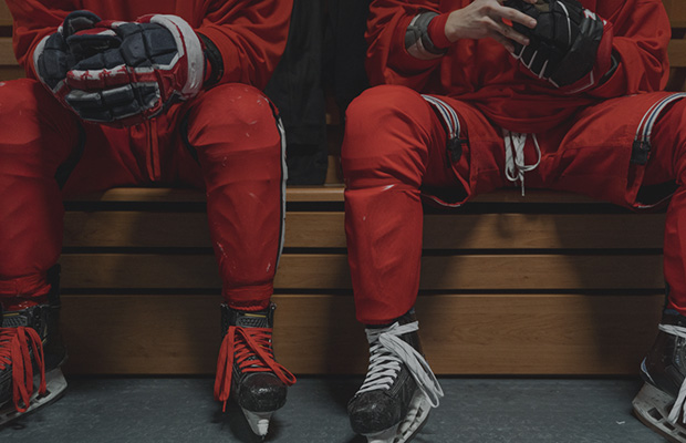 two hockey players in gear on ice sitting