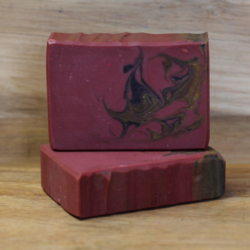 A maroon red bar of soap with black and yellow swirls.